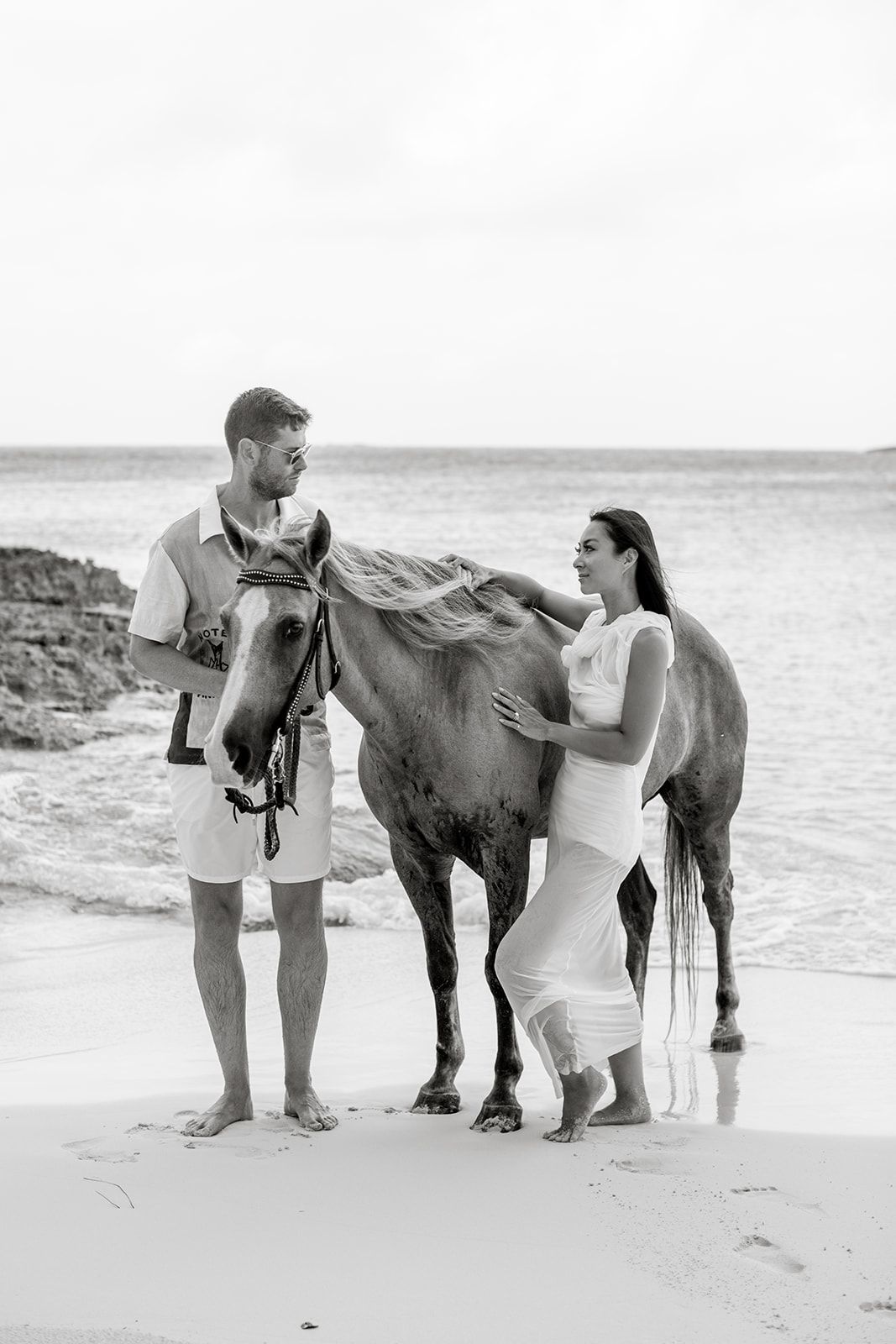 Man and woman stand next to horse on beach of Anguilla