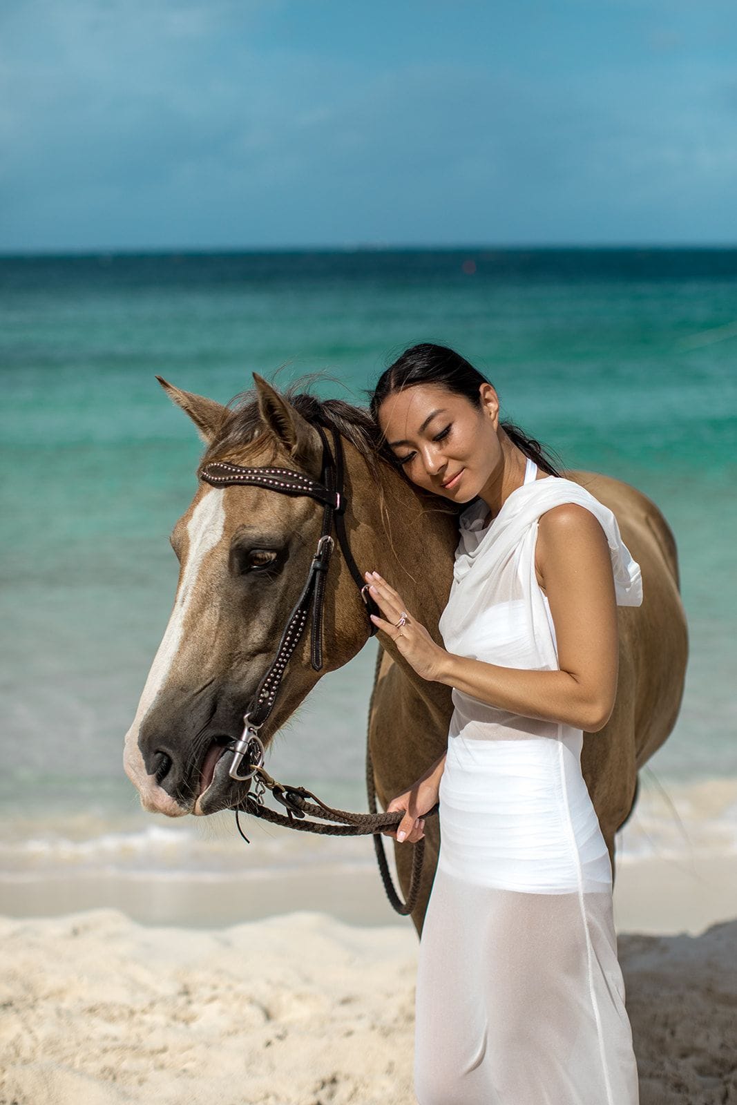 Woman stands next to horse on Anguilla beach