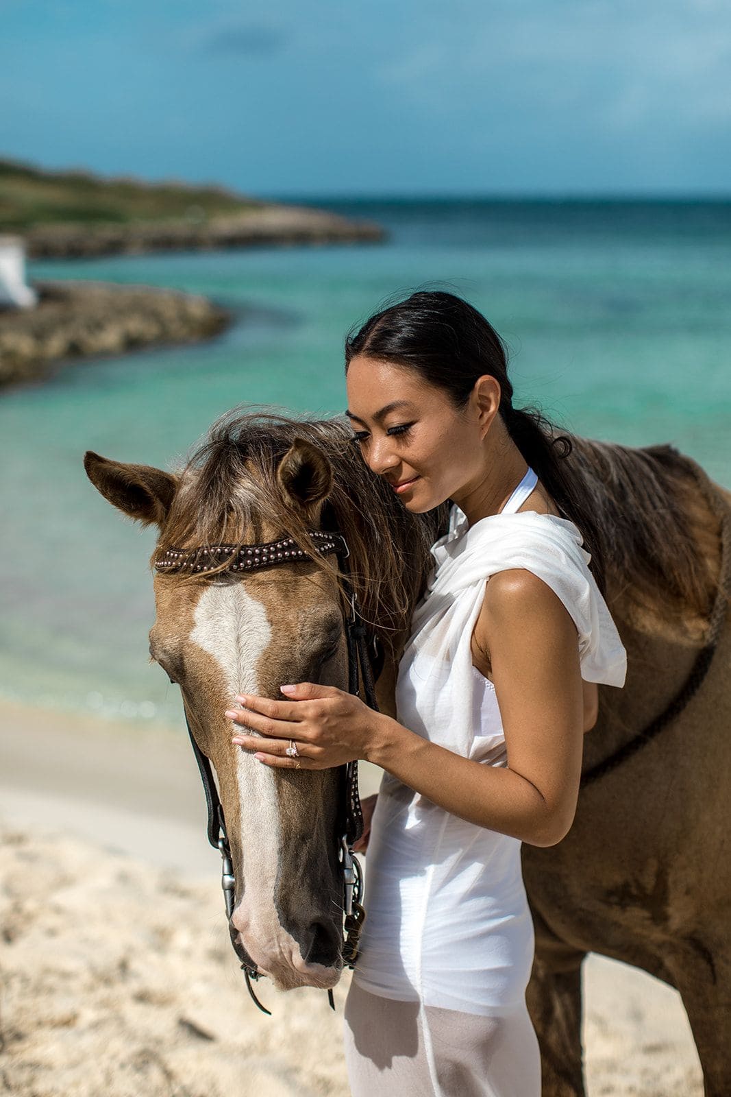 Woman pets horse on Anguilla beach