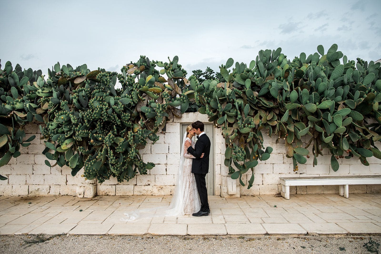 Bride and groom in front of cactus and Masseria Potenti wedding venue in Puglia Italy