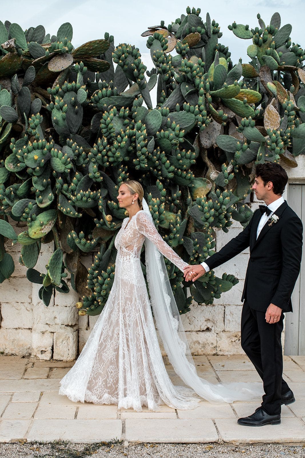 Bride and groom walk on sidewalk next to cactus in Puglia Italy