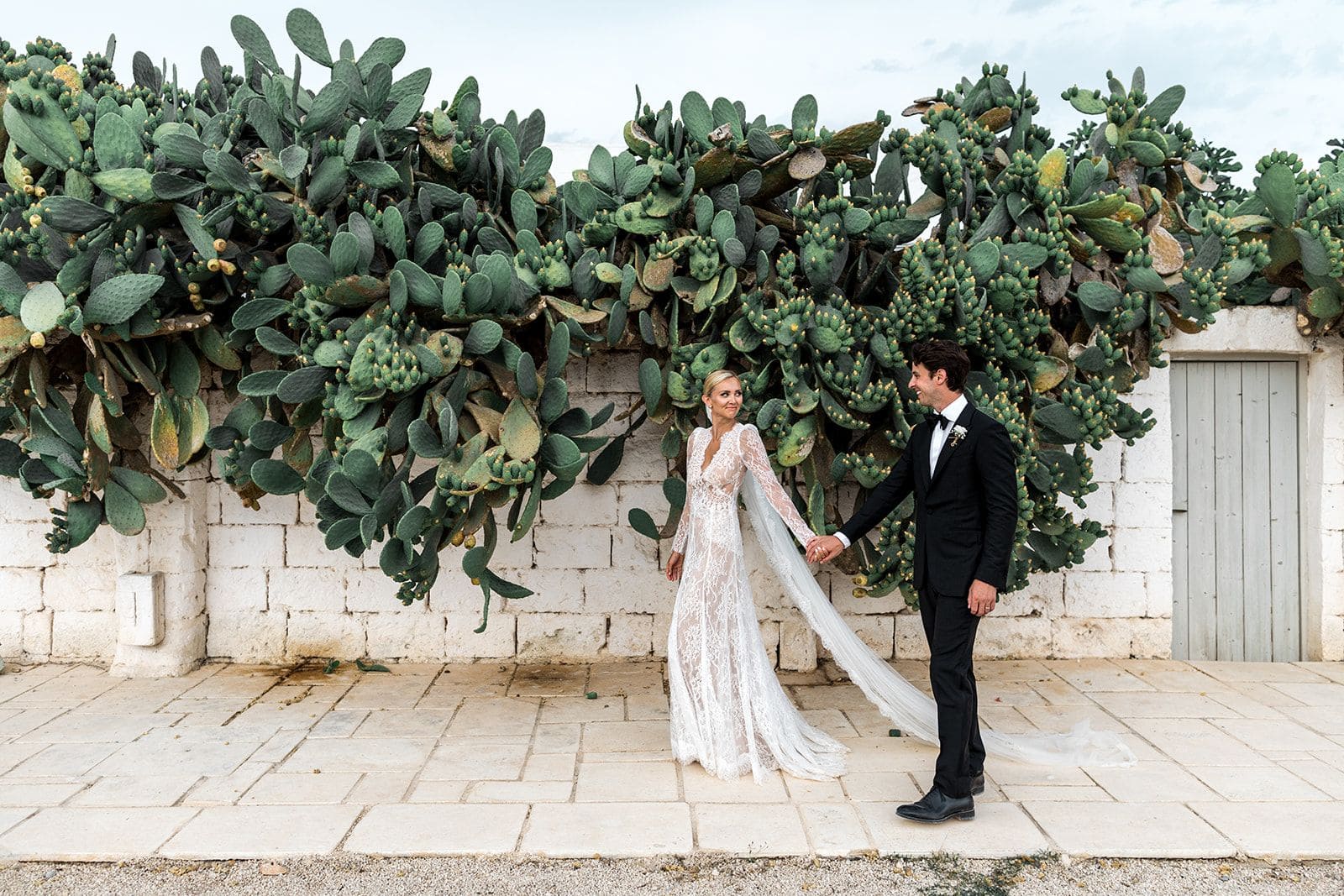 Bride and groom walk past cactus in Puglia Italy