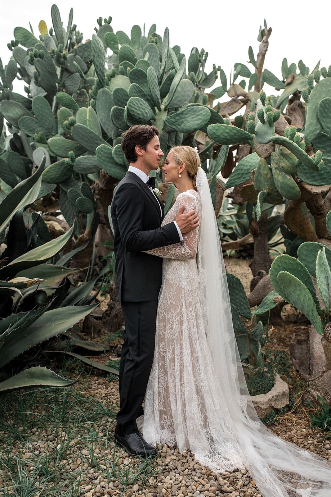 Married couple stand together near cactus in Puglia Italy after destination Masseria Potenti wedding