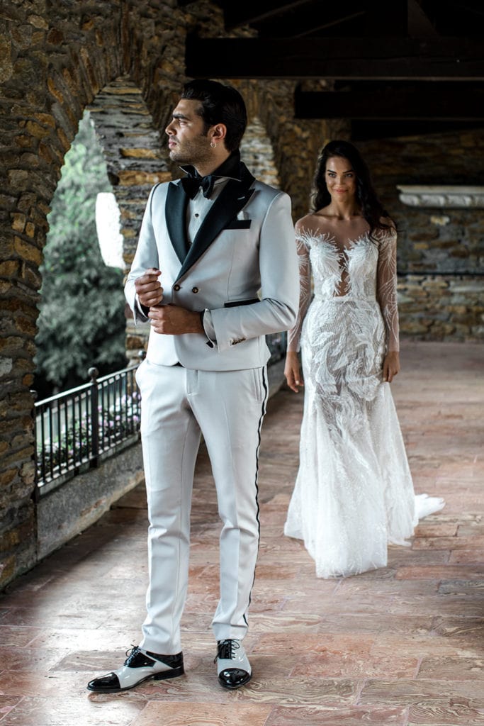 Groom wears white tuxedo with black accents for groom wedding attire
