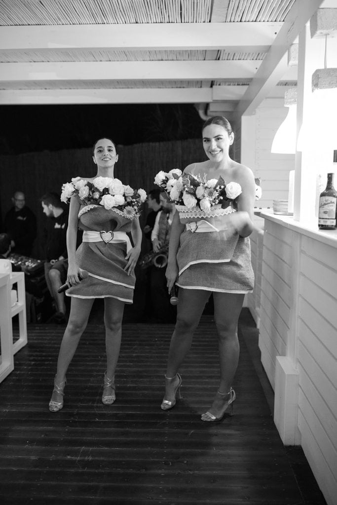 Two women stand in couture dresses made to look like flower centerpieces. 