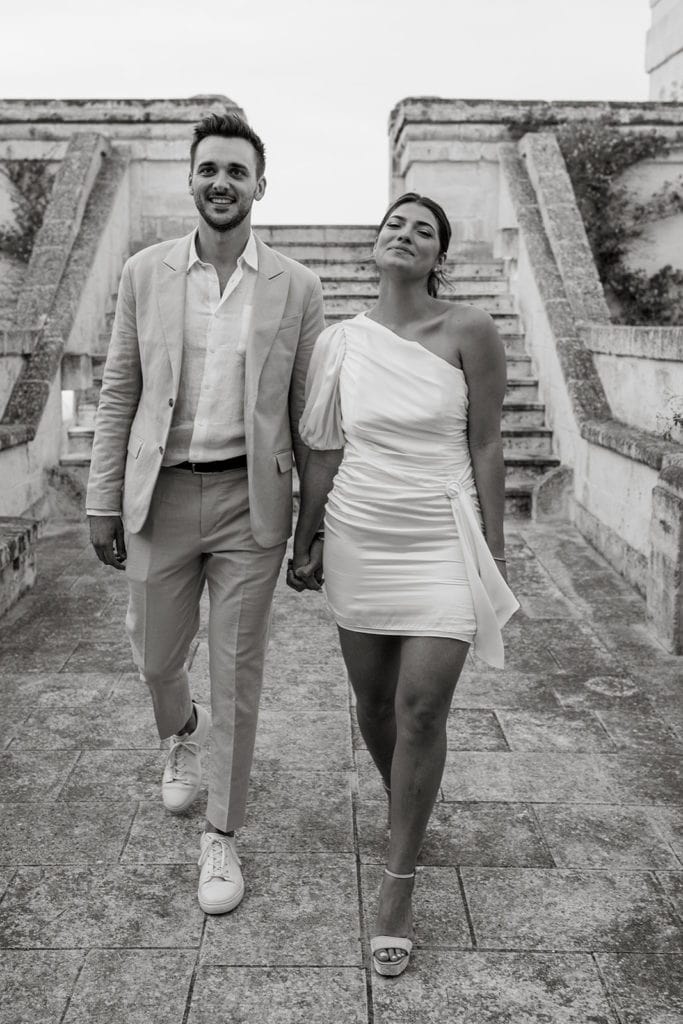 A man and woman walk hand in hand down the steps of the Terrazza Quattro Torri. 