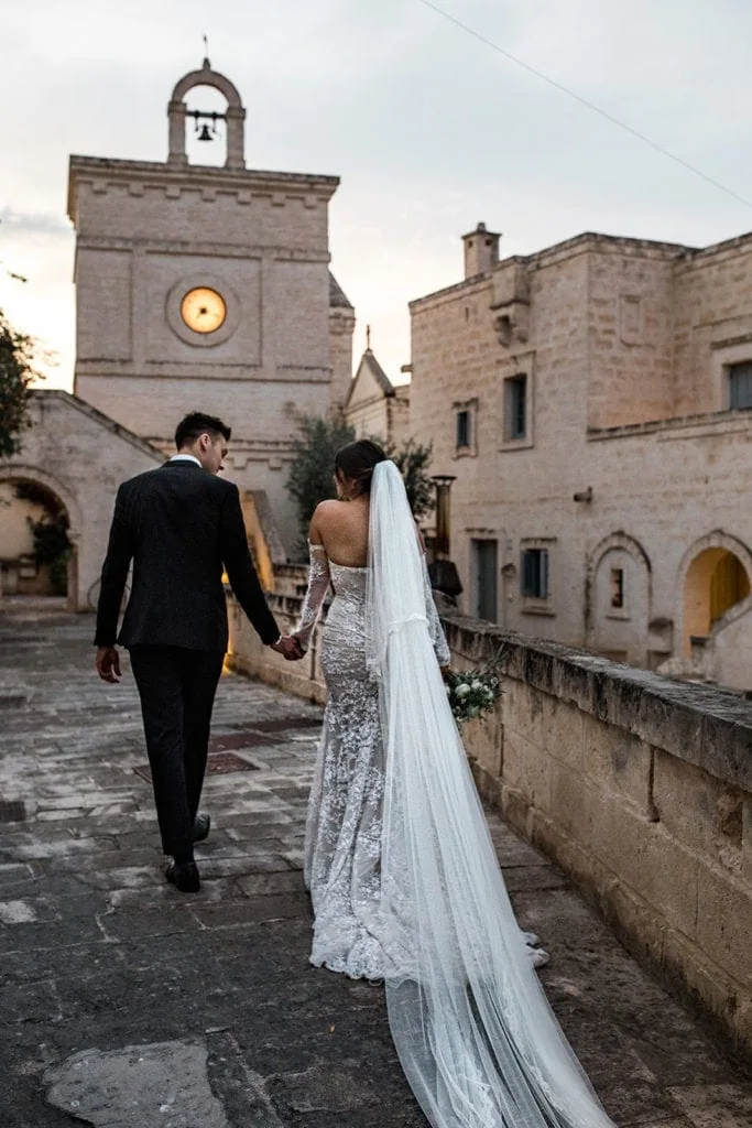 A bride and groom walk together at their Borgo Egnazia destination wedding ceremony. 