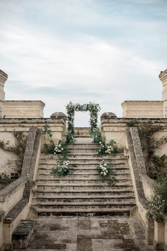 Floral designs line the stairs to the top of the Borgo Egnazia for a wedding ceremony. 
