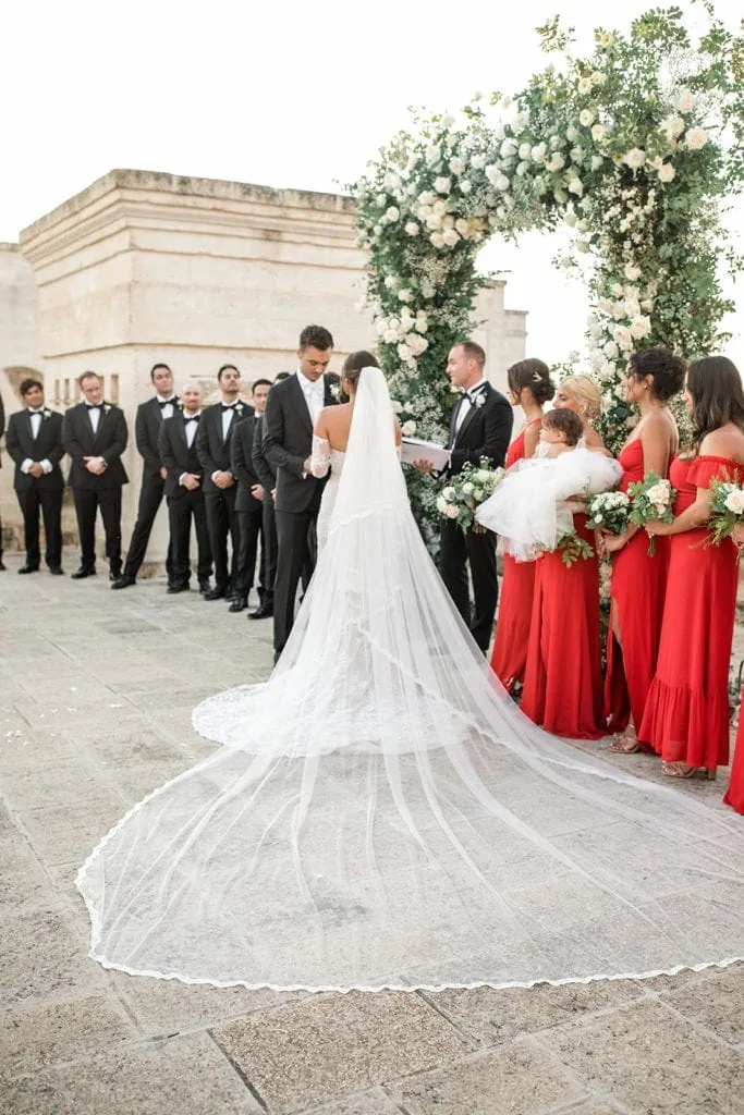 A bride's cathedral-length veil is draped behind her at her Puglia, Italy destination wedding ceremony. 