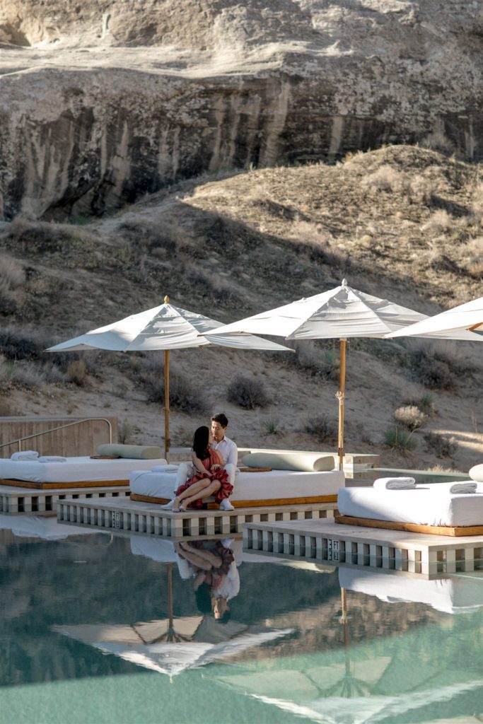 A man and woman sit on pool chaises at the resort pool at Amangiri. 