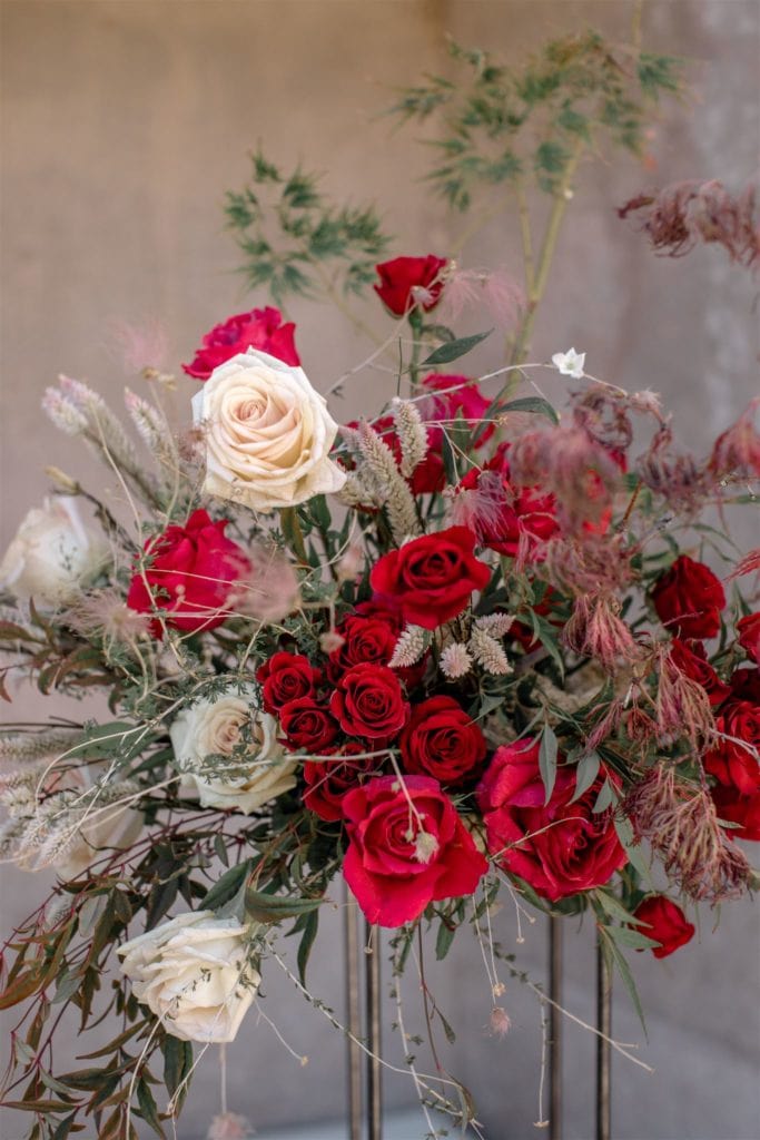 Bright red flowers with touches of white and pink create a large wedding centerpiece. 