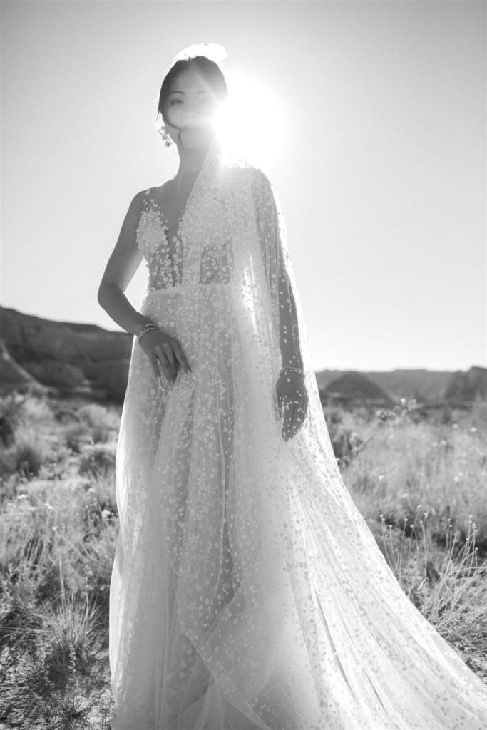 A black and white portrait of a bride wearing a Berta wedding gown with a matching veil in the canyons of Utah. 