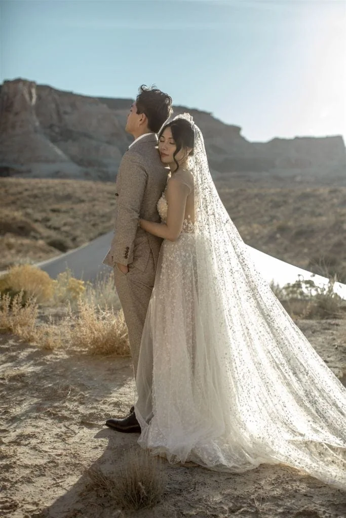 A bride stands behind her groom in the canyons of Utah during their Amangiri elopement.