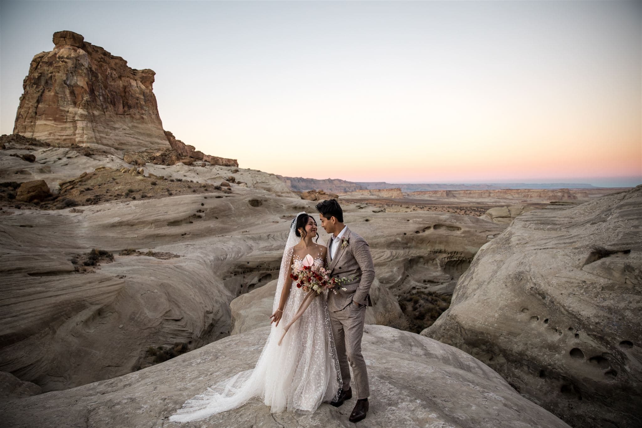 A bride and groom look at each other on their Amangiri wedding day at sunset among the plateaus.