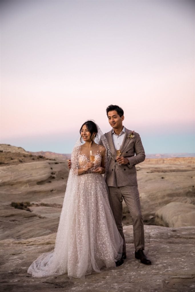 A bride and groom toast with champagne in the plateaus during their Amangiri wedding elopement. 