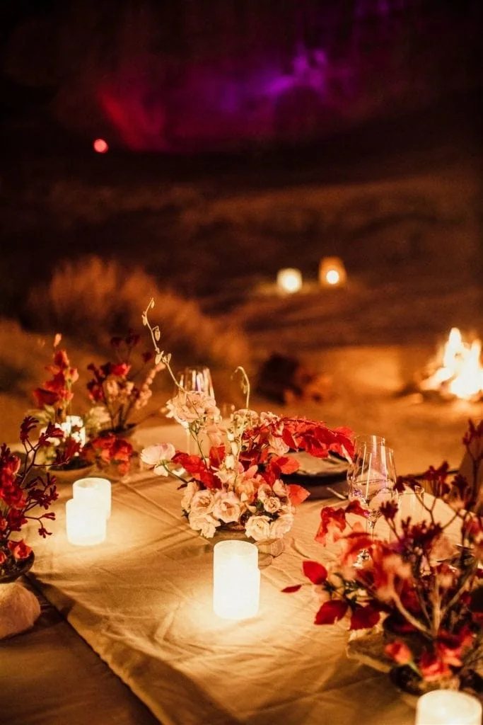 Pink and red flowers in a table centerpiece line a banquet-style table at an Amangiri reception. 