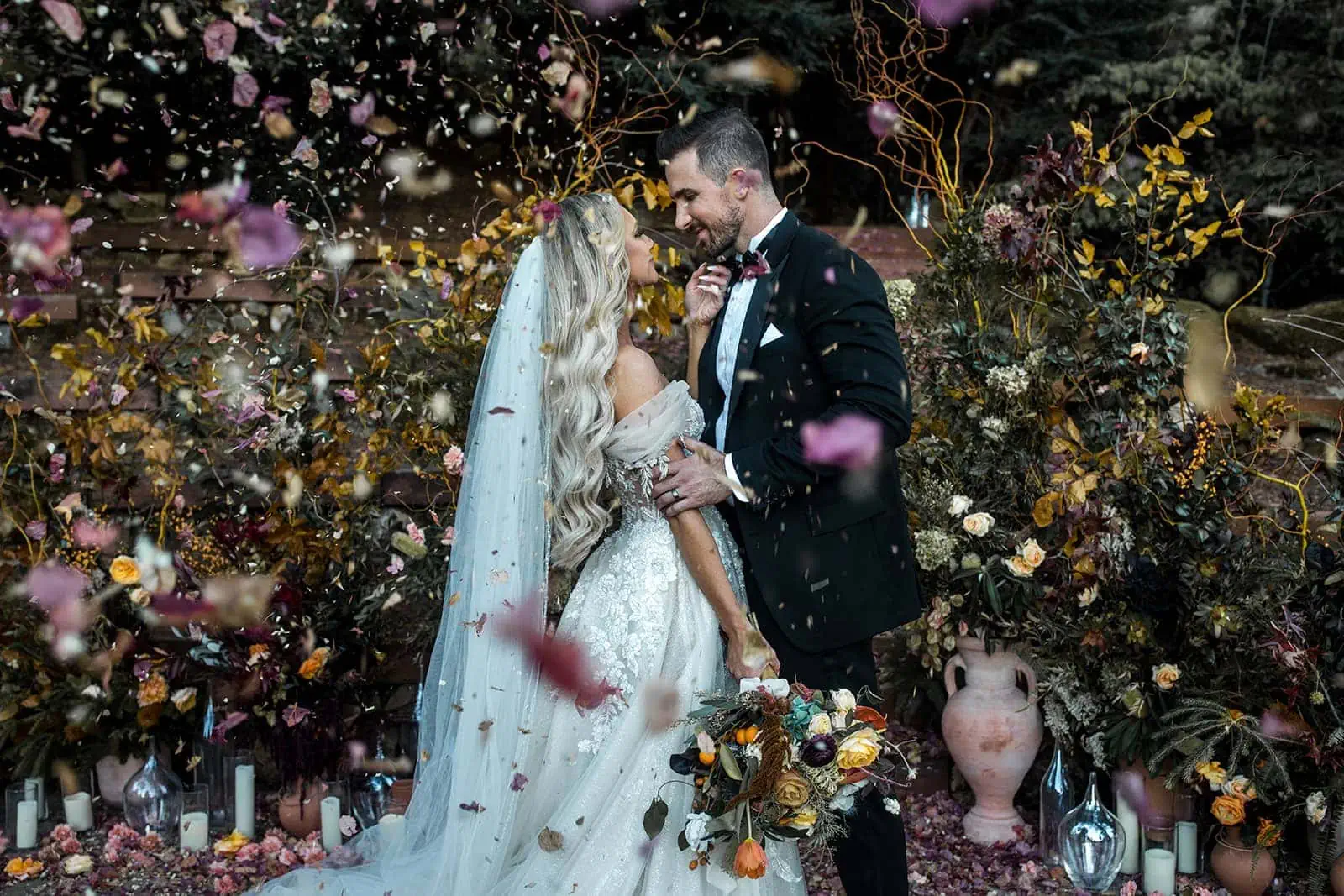 A bride and groom stand together as flower petals float around them in the Northern California breeze.