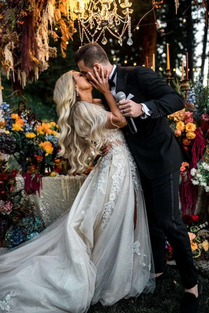 A bride and groom kiss in front of their sweetheart table at the reception after the groom makes a toast. 