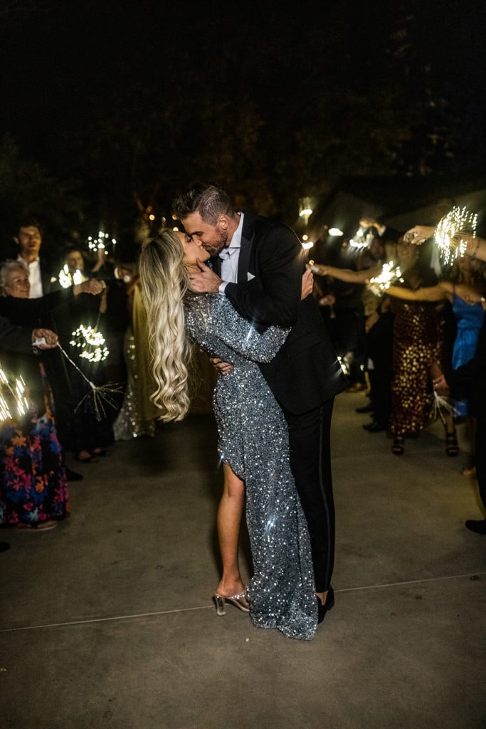 A groom stops her bride and kisses her as they make their way through a sparkler grand exit. 