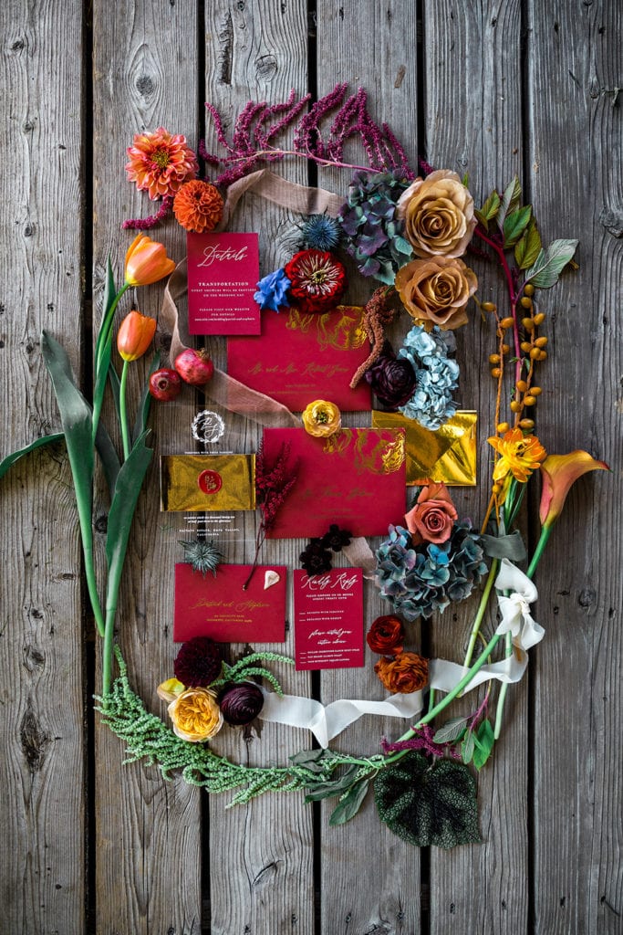 A wine-colored invitation suite is styled with bright florals from a vibrant, jewel-toned wedding. 