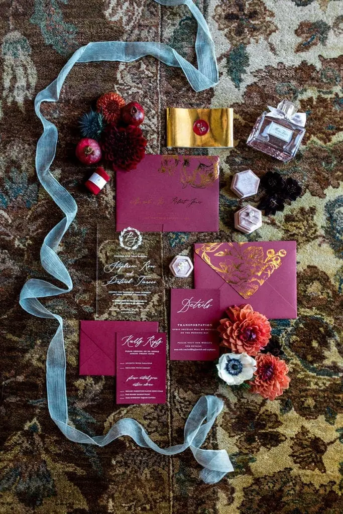 A merlot wine-colored invitation suite is styled with other bridal details and wedding day florals. 