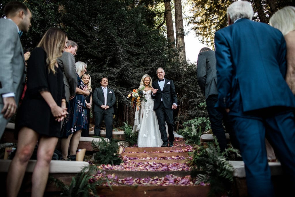 A bride and her father walk down the steps to the ceremony site at a Calistoga Vineyard Estate wedding. 