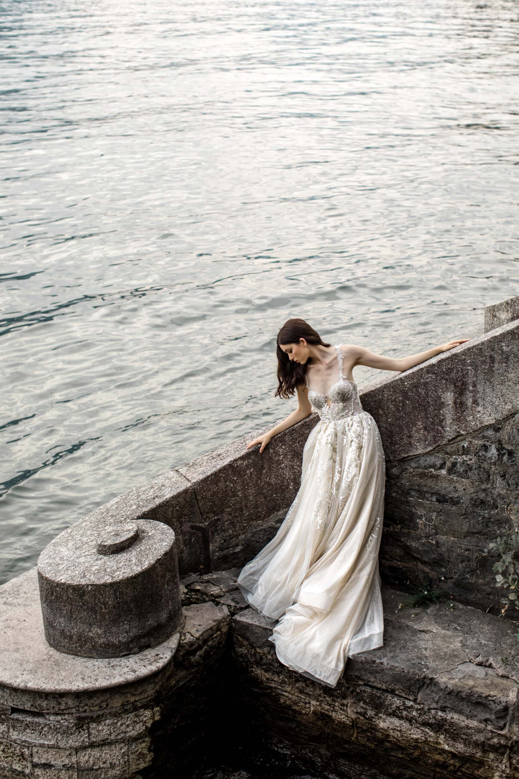 Model wearing bridal gown at water's edge Lake Como