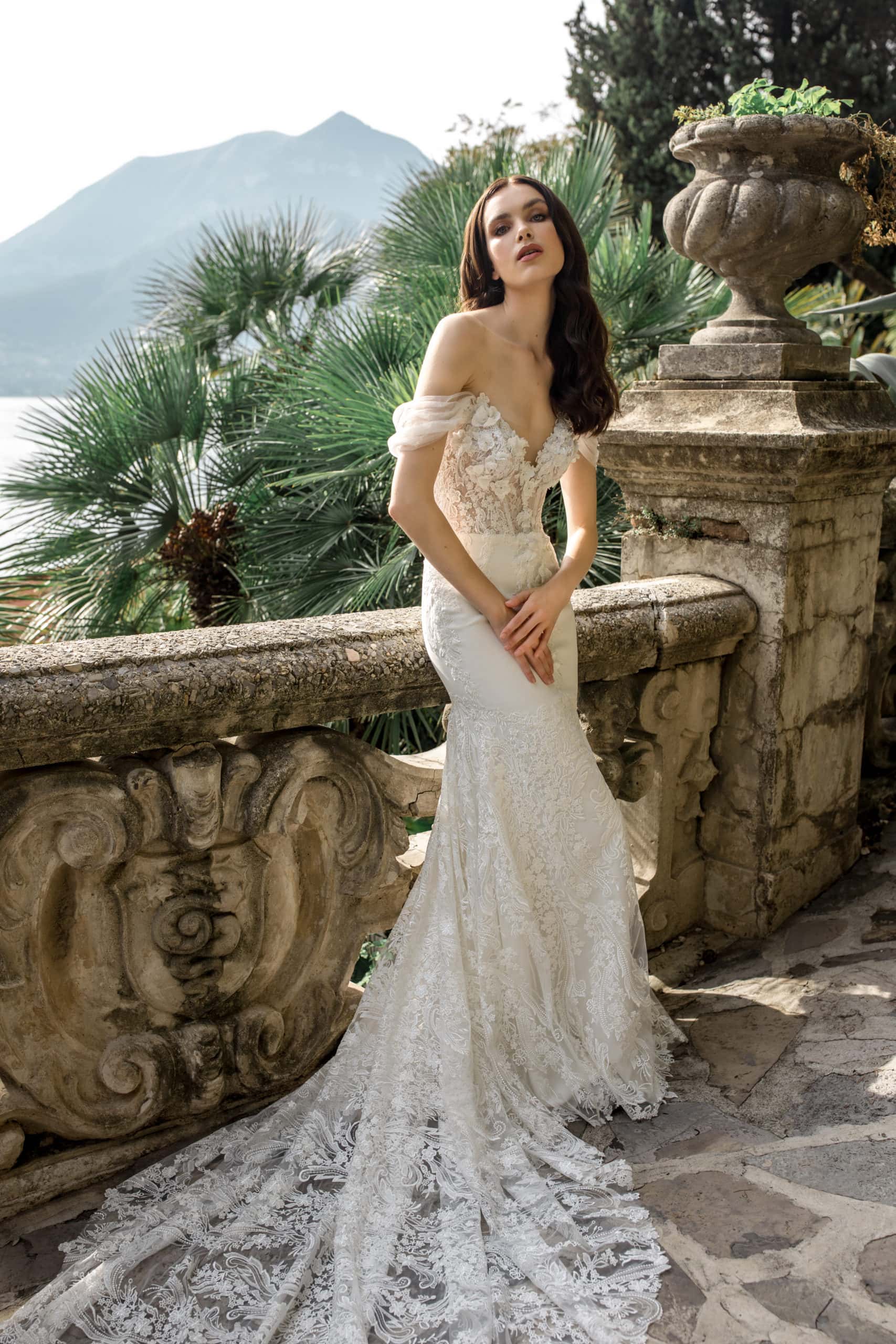 Model leans against banister in lace bridal gown on Lake Como
