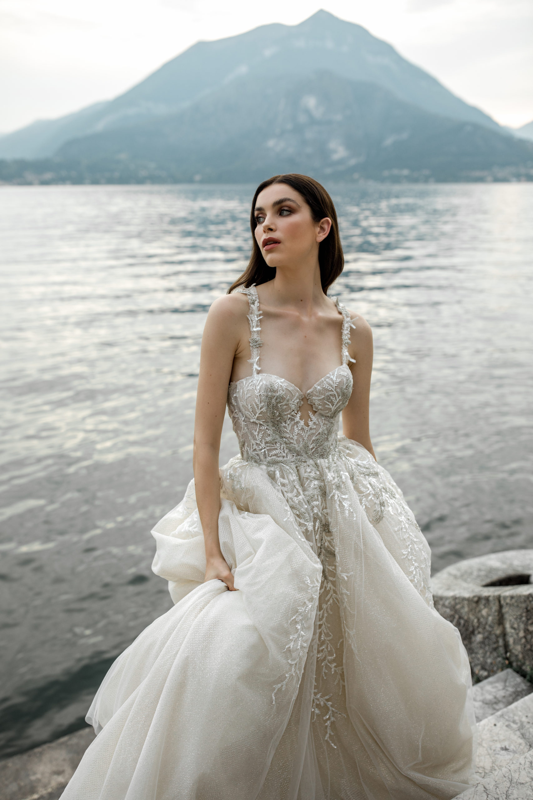 Model wears bridal ball gown with Lake Como view in background