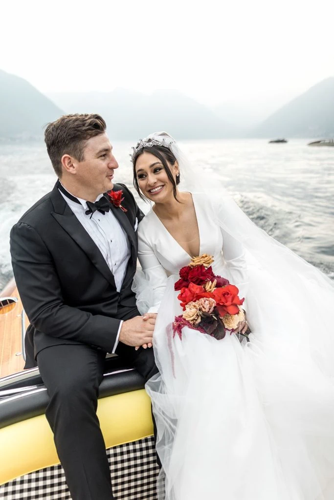 Bride and groom sit together in Italian boat for tour across Lake Como