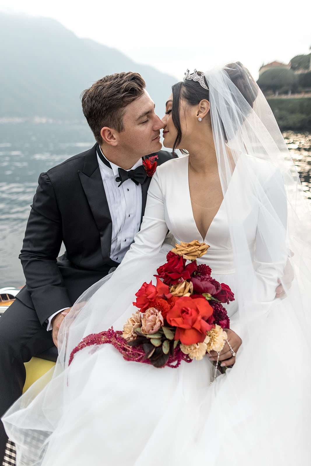 Bride and groom kiss on boat on Lake Como