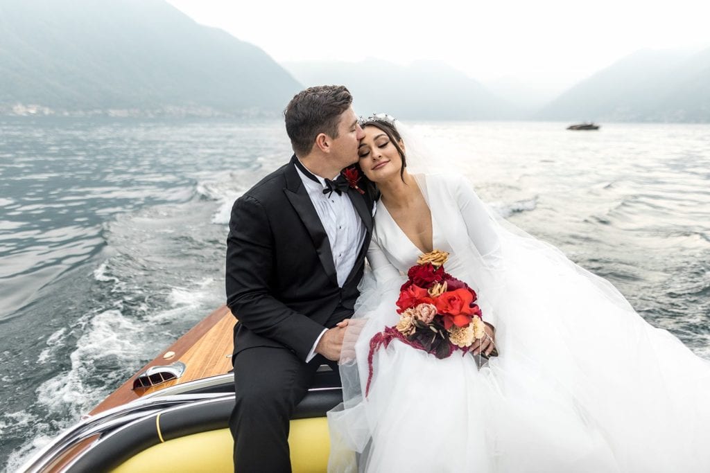 Groom kisses bride's forehead during couple's portraits on Lake Como boat tour
