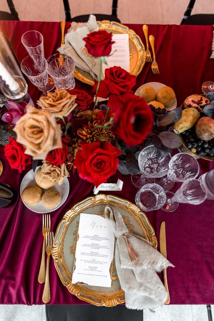 Jewel-toned reception tablescape with deep reds, light peaches, and gold