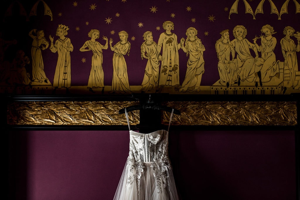 A corset bodice of a Berta wedding gown hangs in front of a Villa Clara ornate wall