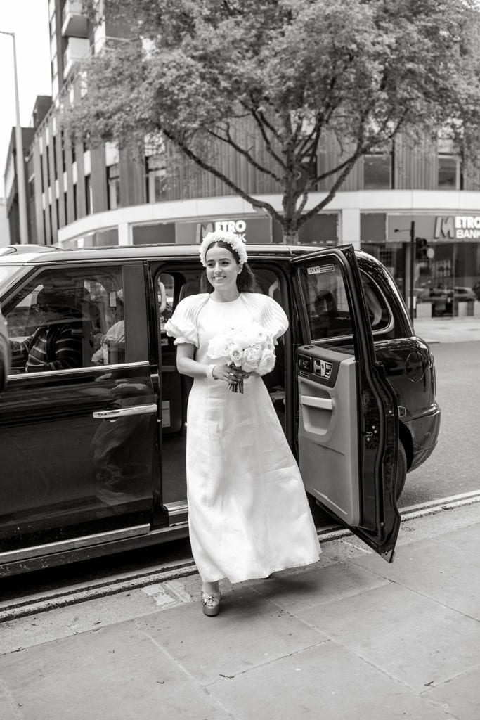 Bride steps out of car at courthouse before London elopement ceremony