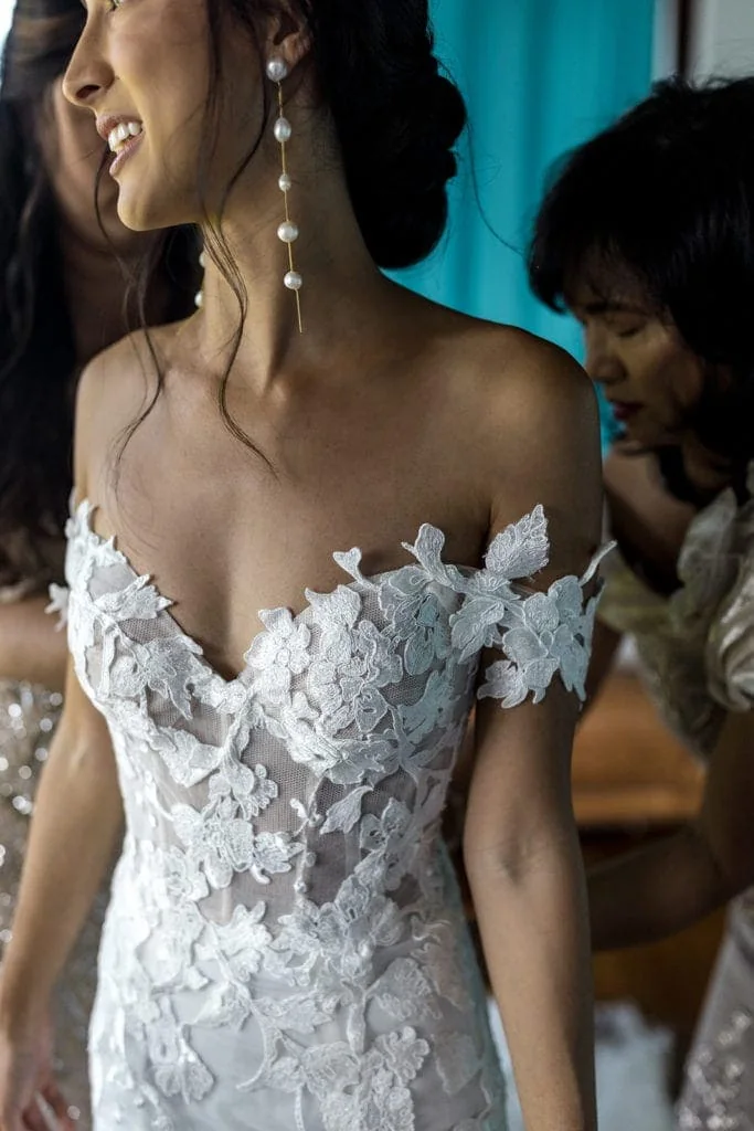 Bride in a Monique Lhuillier wedding gown gets dressed with her mother's help