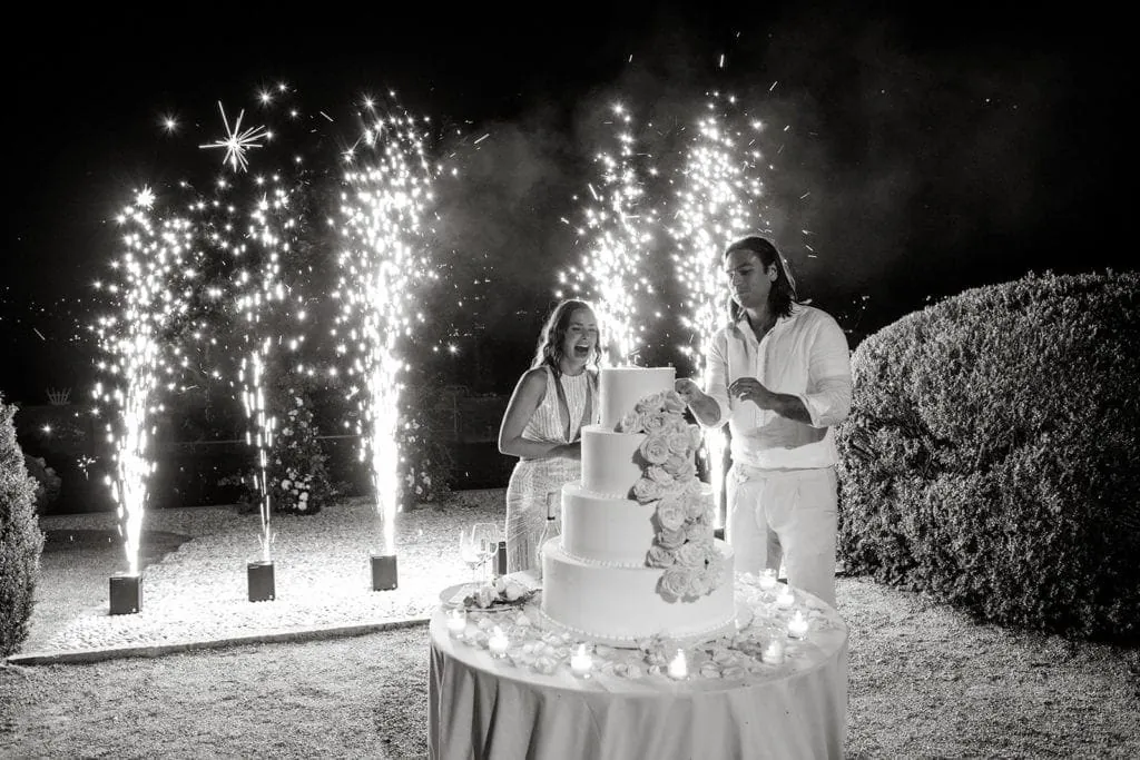 Bride and groom cut cake at Villa Erba wedding venue with fireworks in the background