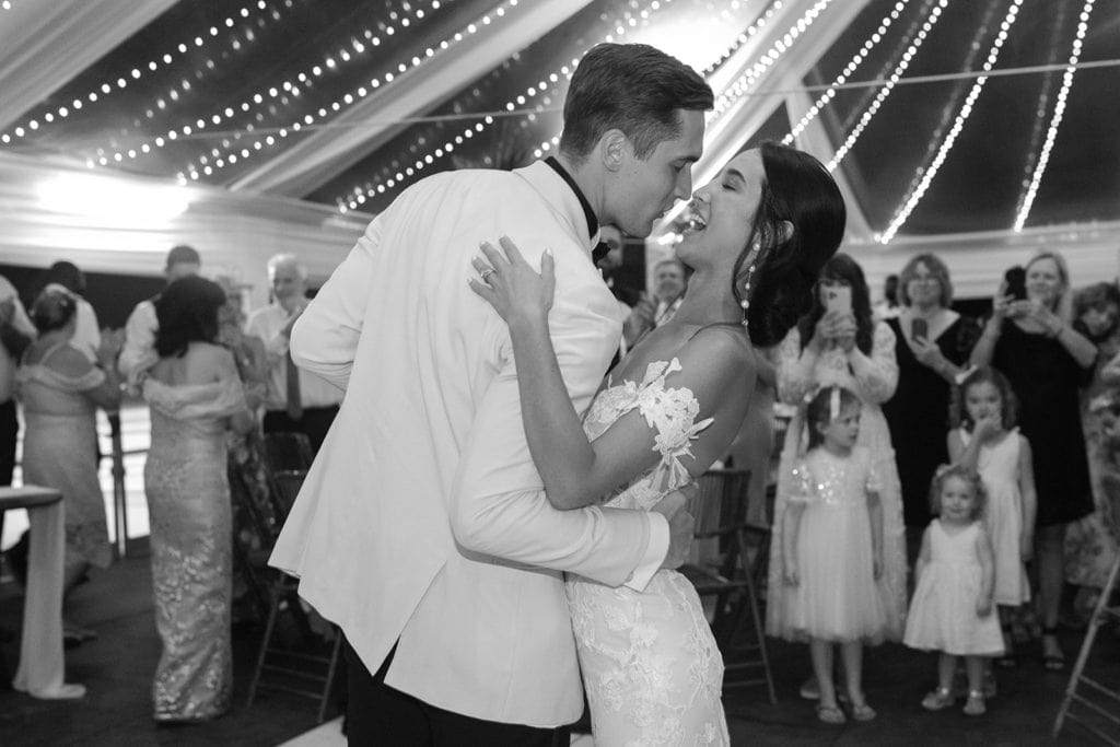 A groom dips his bride while dancing at their wedding reception