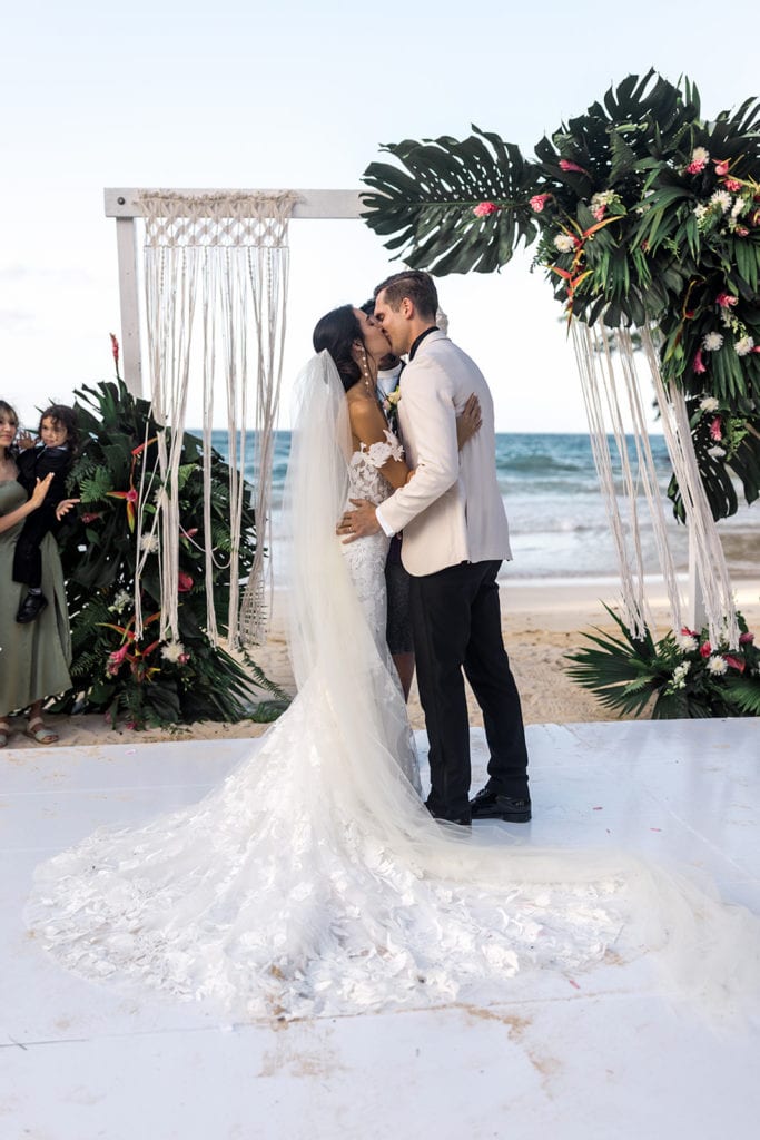 Bride and groom kiss after getting married at the altar of their wedding on the beach in Jamaica