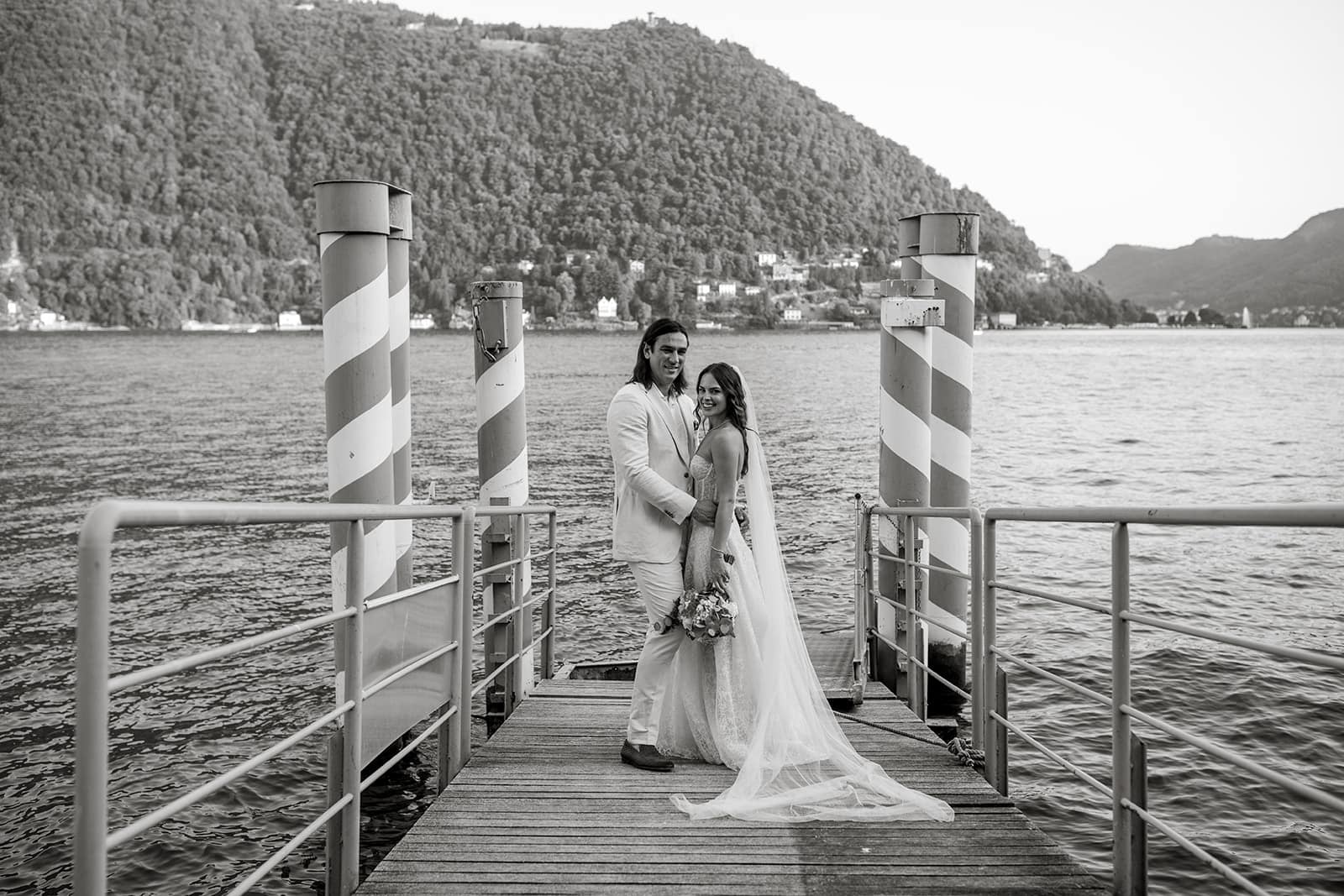 Bride and groom stand together on dock at Lake Como during destination wedding