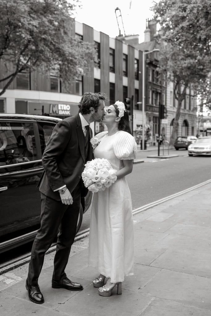 Bride and groom kiss on streets of London before their elopement ceremony