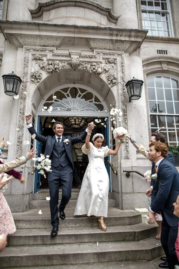 Bride and groom, who wears groom wedding attire ideas, exit London courthouse after getting married