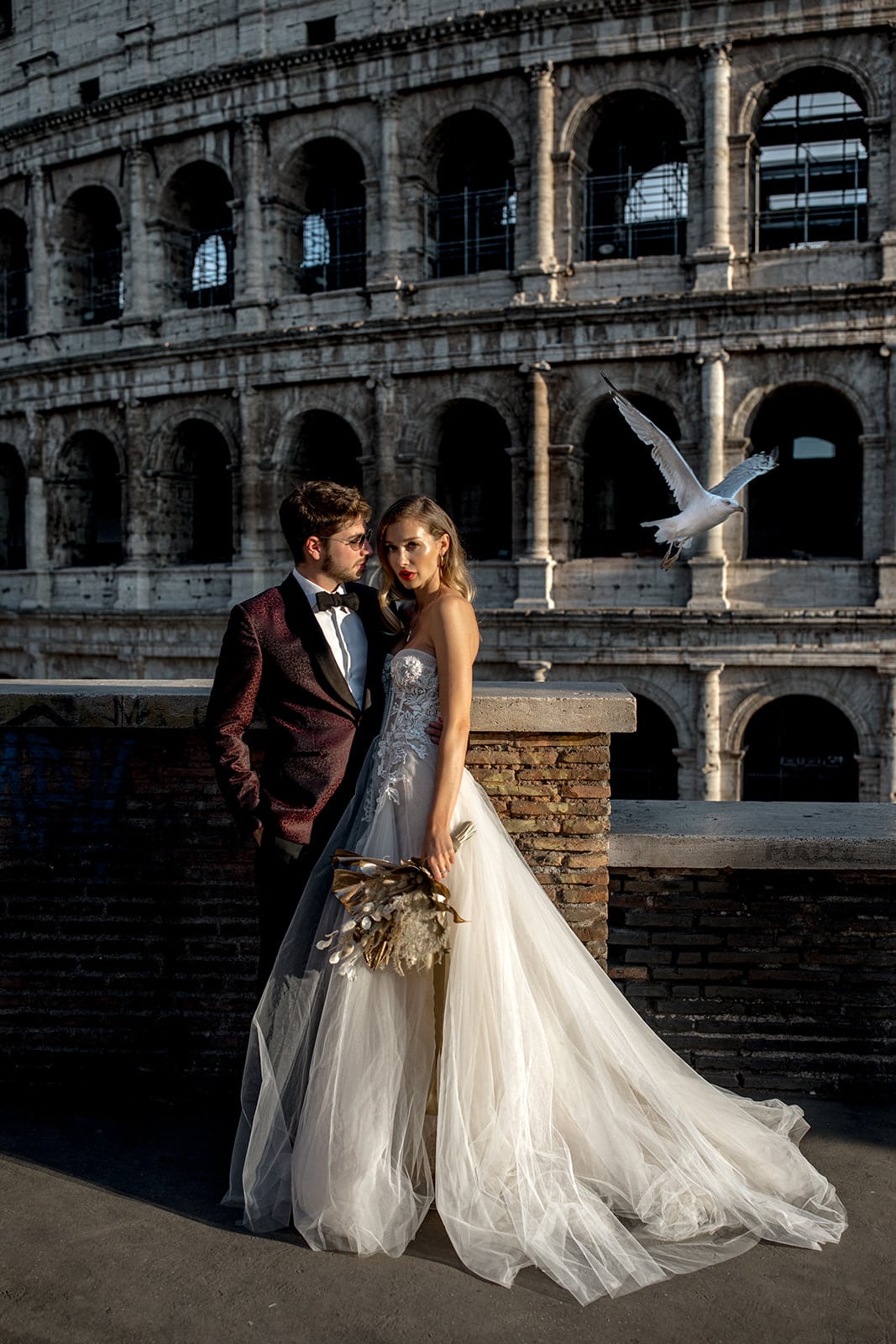 Bride and groom stand together in front of Coliseum in Rome, Italy