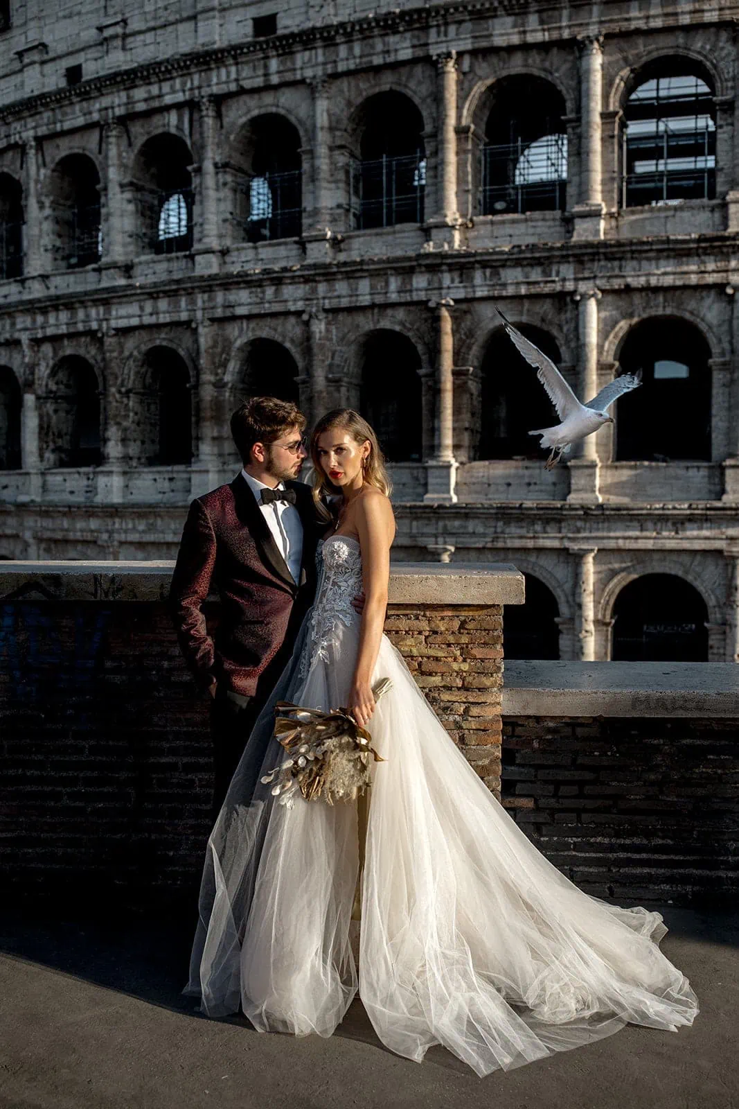 Bride and groom stand together in front of Coliseum in Rome, Italy