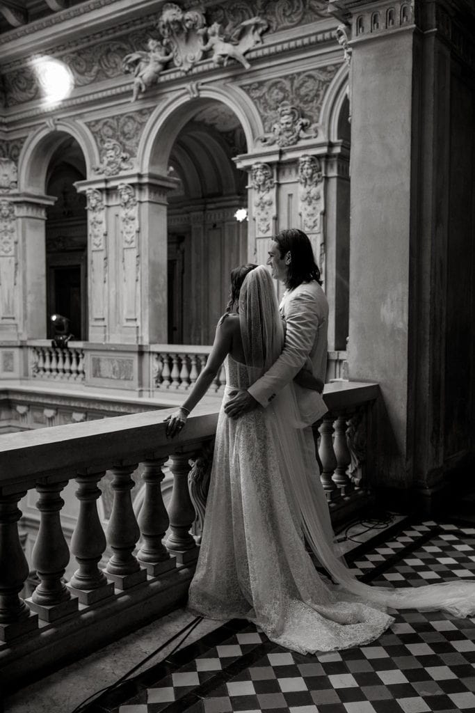 Bride groom stand together at railing in wedding venue
