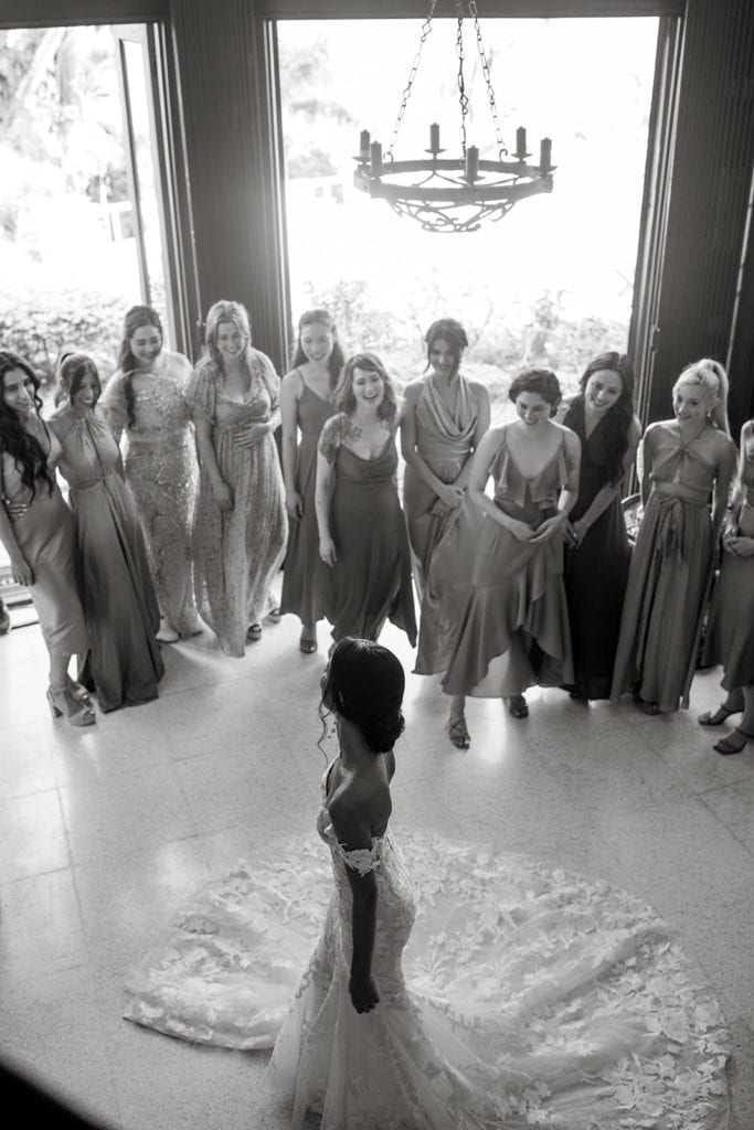 Bride in a trumpet-style wedding gown has a first look with her bridesmaids