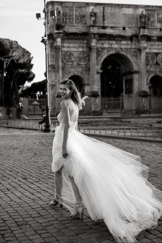 A bride grins at the camera as she walks down the street in Rome