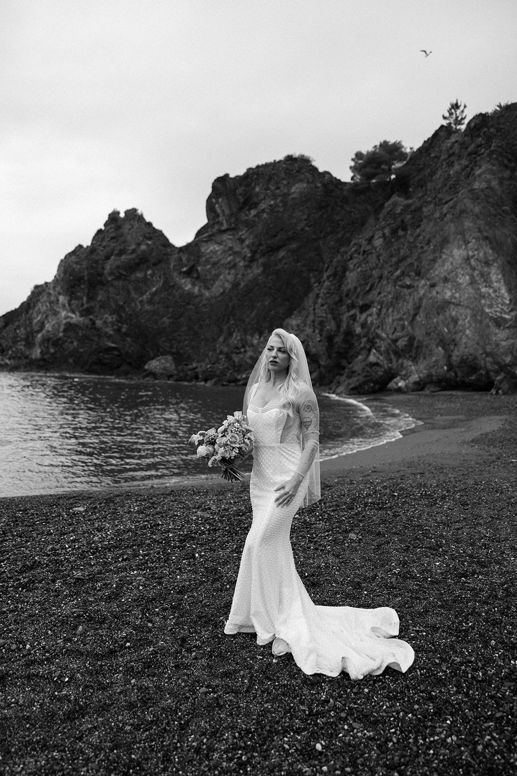 Bride stands on empty beach in Cinque Terre