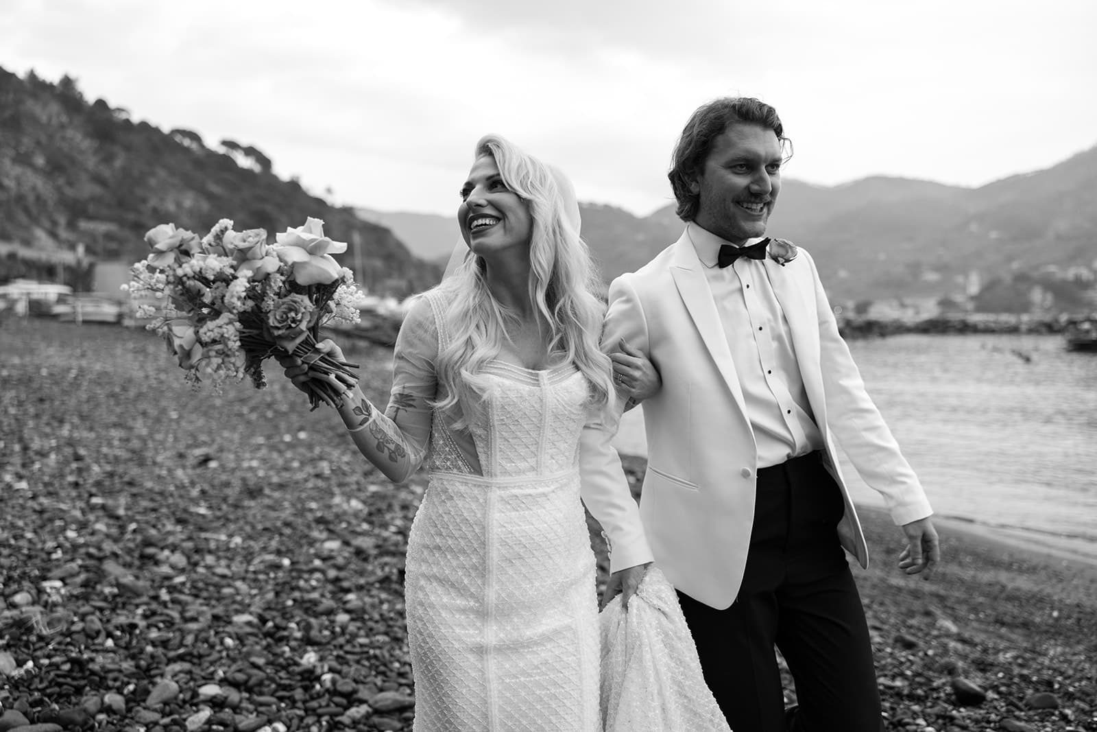 Bride and groom walk down private beach in Liguria, Italy