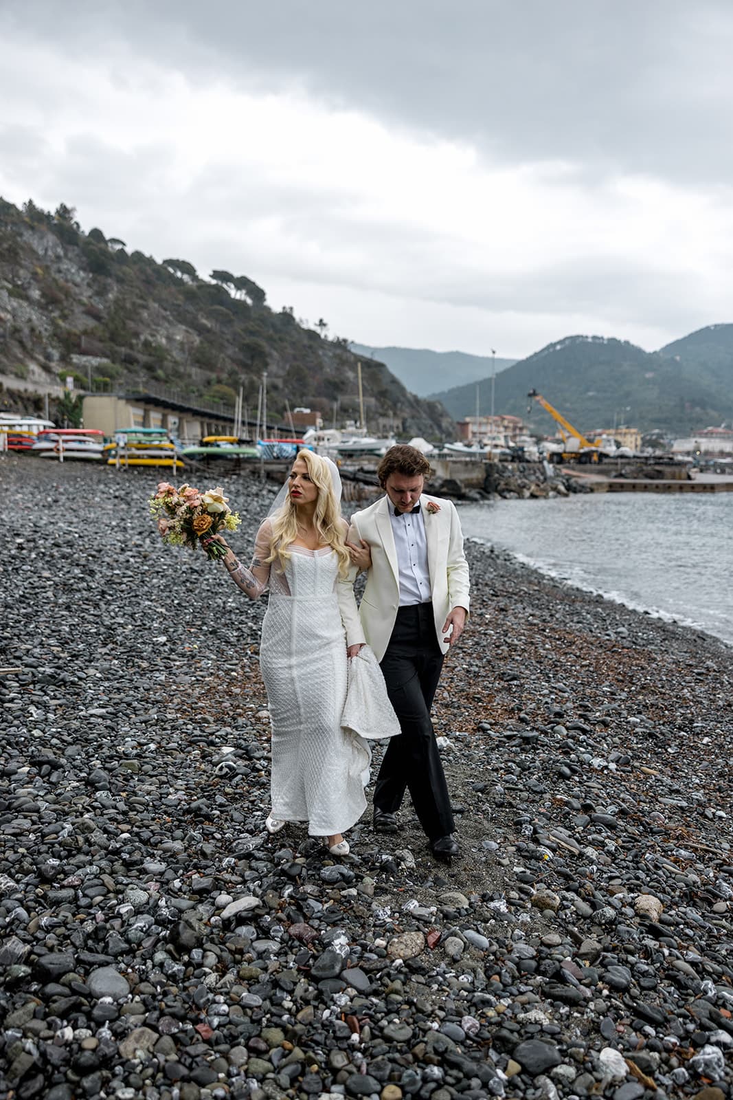 Bride and groom walk down beach after Cinque Terre wedding
